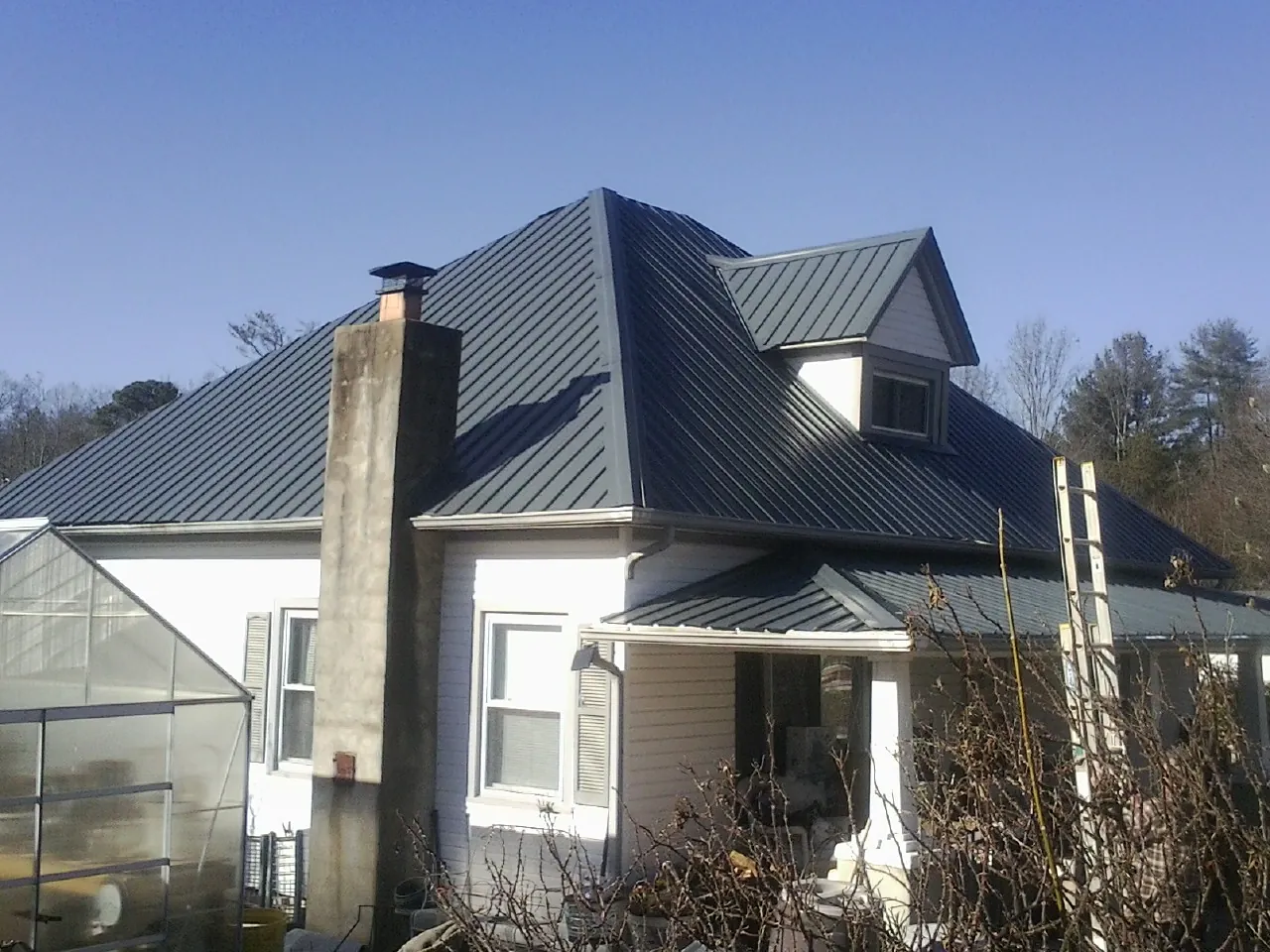 Dark blue standing seam metal roof on a white farmhouse with dormer — Slate & Tile Roof Repair by Roofing Brothers in North Easton