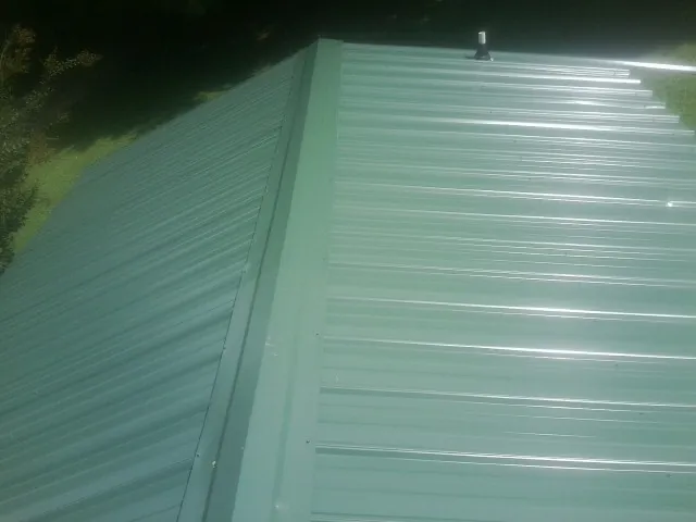 New green metal panels meeting at the ridge of a roof — Flat Roof Repair work by our crew in North Easton