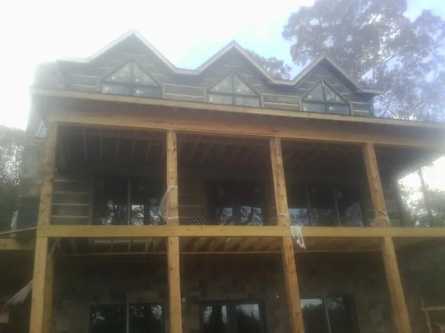 Dormers and porch framing on a large log home under construction — Roof Coating work by our crew in North Easton