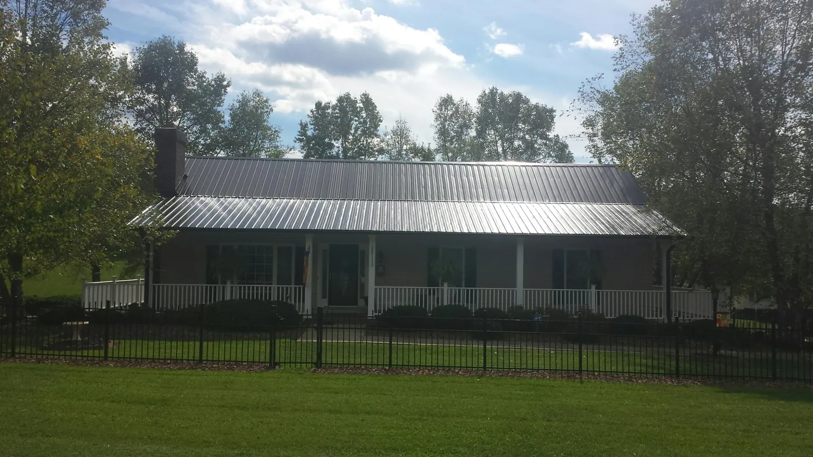 Gray metal roof on a brick ranch with a full width front porch — Gutter Guard Installation work by our crew in North Easton