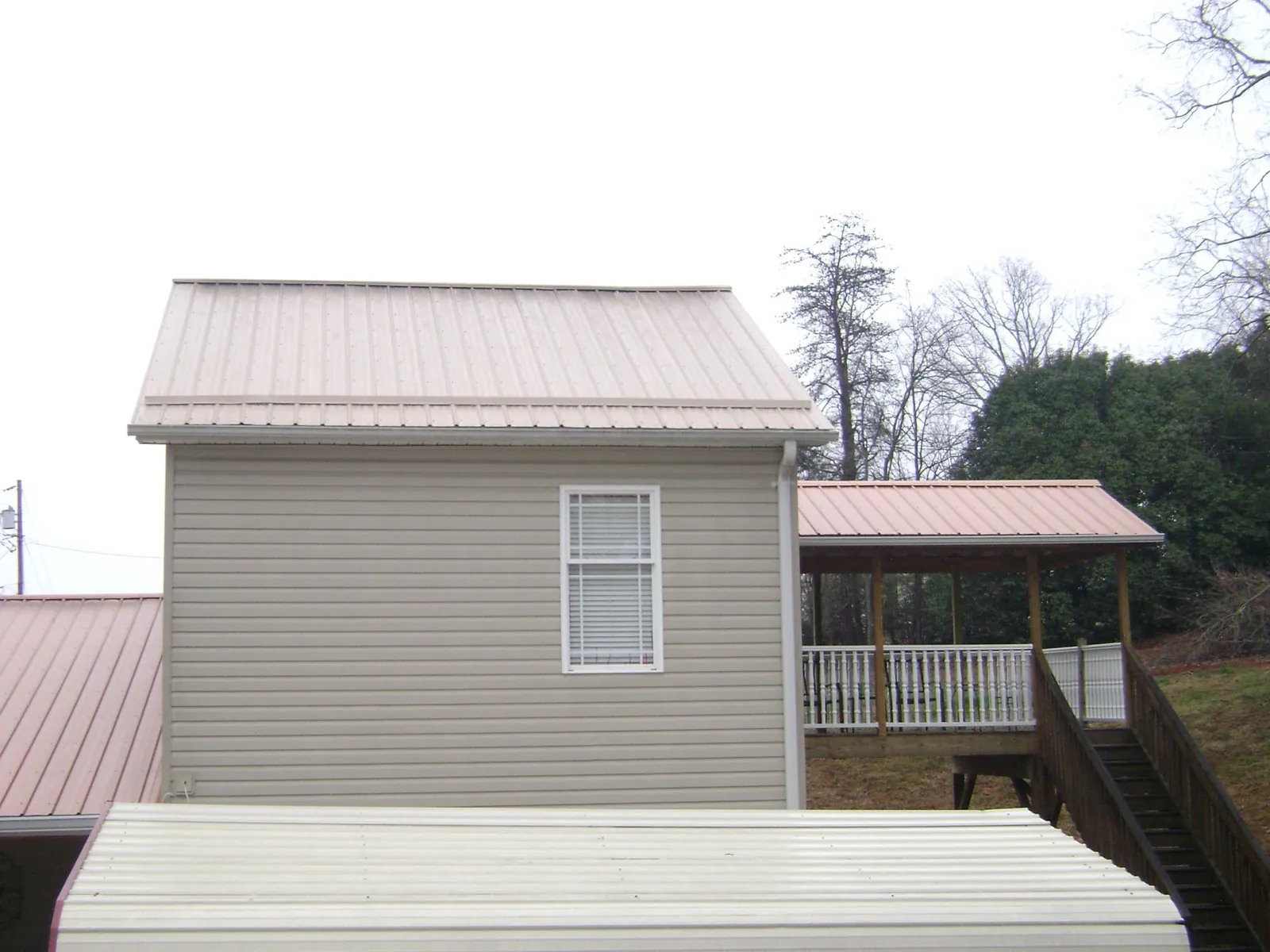 Tan metal roofs on a two story addition and attached porch, from a Roof Replacement job in North Easton