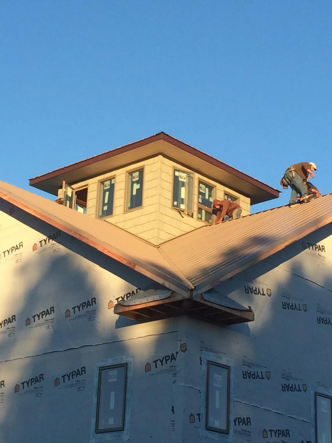 Roofers working around a rooftop cupola on a new metal roof at sunset — Roof Waterproofing in North Easton by Roofing Brothers